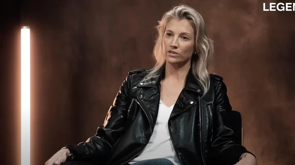 Audrey Lefèvre pose en veste en cuir noir et haut blanc sur un fond marron.