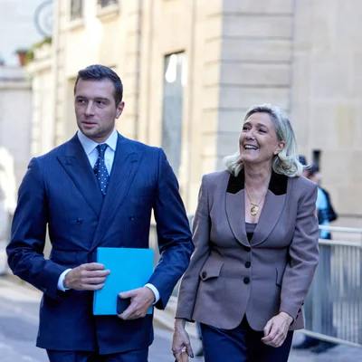 Jordan Bardella et Marine Le Pen marchant ensemble lors d'un déplacement.