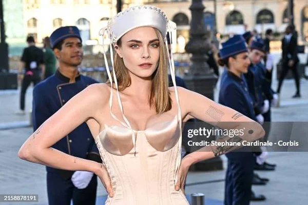 Cara Delevingne portant une tenue blanche lors d'un événement officiel.