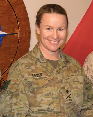 Susan Coyle en uniforme militaire australien devant un emblème en bois.