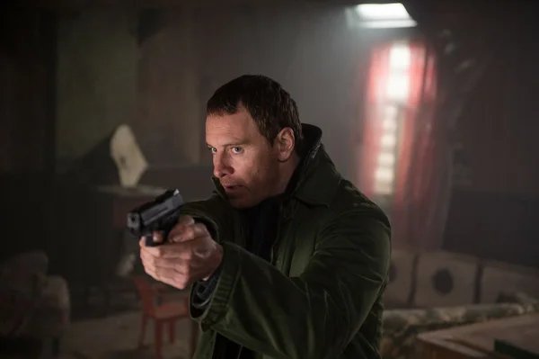 Scène intense montrant le protagoniste armé dans un intérieur sombre et feutré.