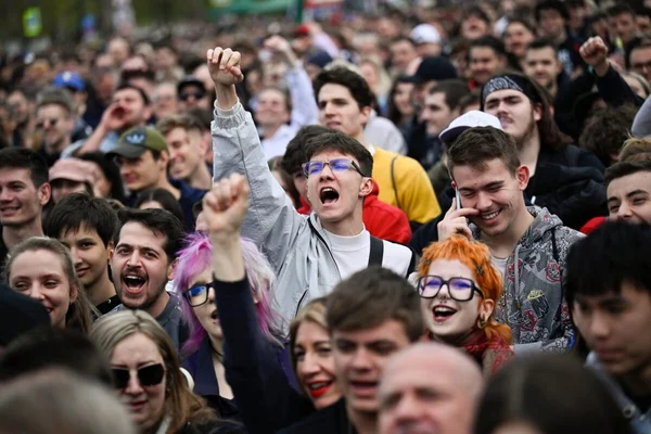 Foule en protestation avec des poings levés et un orateur criant.