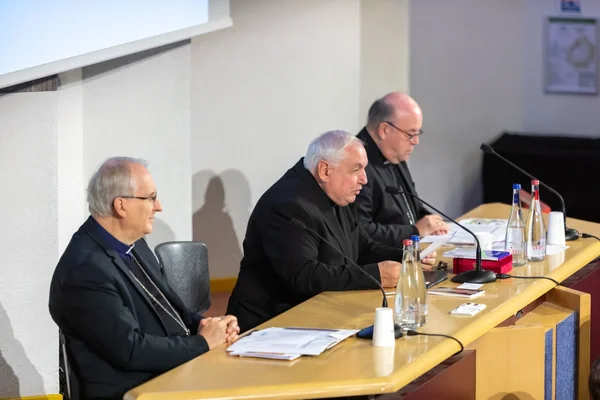 Trois ecclésiastiques participant à une conférence de presse.
