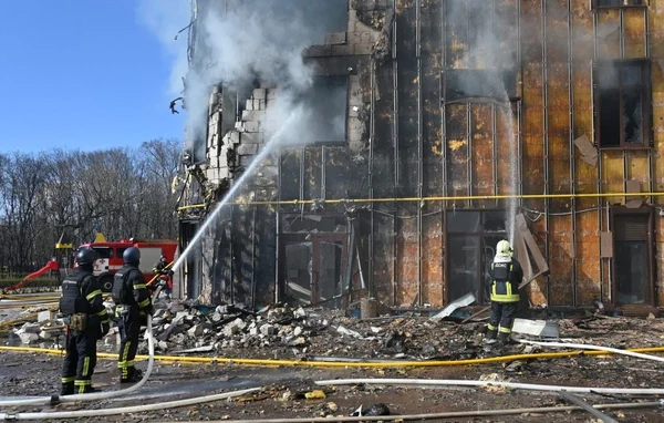 Des pompiers intervenant pour éteindre un incendie dans un bâtiment détruit en Ukraine.