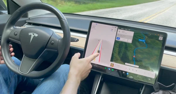 L'écran central d'une Tesla affichant des informations de navigation et le système Autopilot.