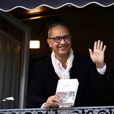 Kamel Daoud, lauréat du prix Goncourt 2024, posant en blazer sombre et lunettes.