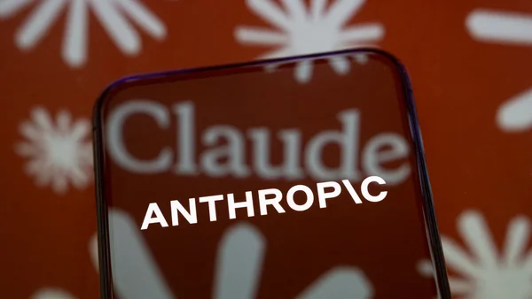 Un smartphone affichant le logo d'Anthropic et l'interface de Claude sur fond rouge étoilé.