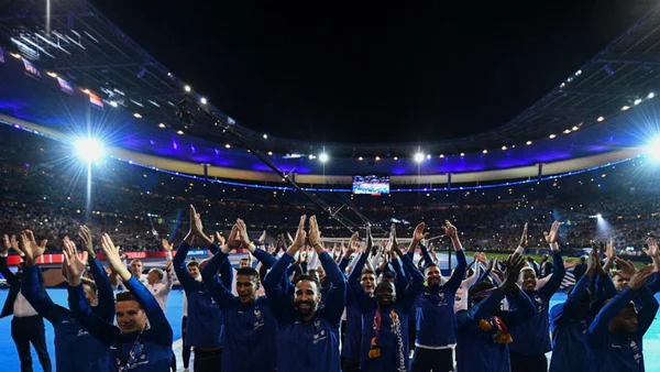 Les champions du monde bleus applaudissant leurs supporters dans le Stade de France en nocturne.