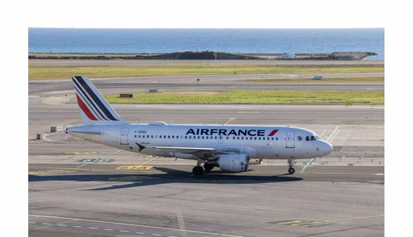 Un avion de ligne Air France stationné sur le tarmac avec l'océan en arrière-plan.