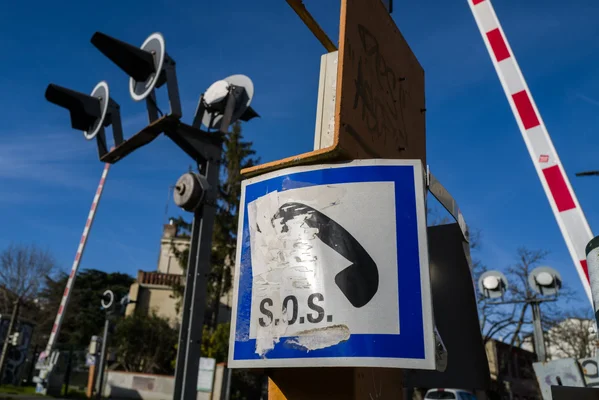 Un panneau de signalisation d'appel d'urgence surplombe un passage à niveau dans le Pas-de-Calais.