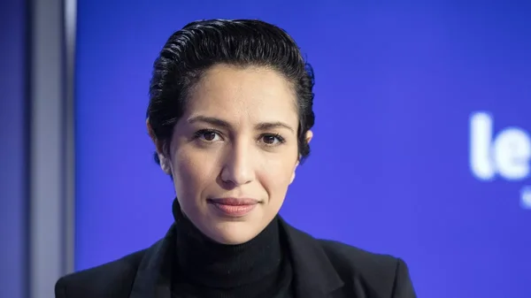 Personne en col roulé et veste devant un fond bleu.