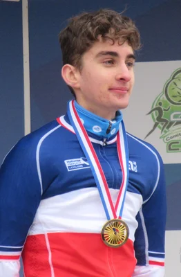 Portrait du cycliste Paul Seixas arborant une médaille d'or et son maillot tricolore.