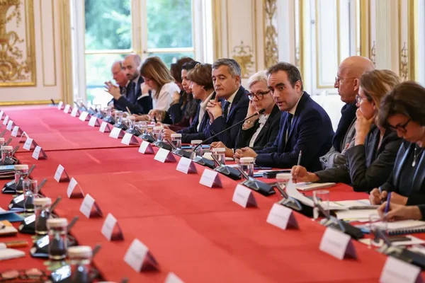 Réunion officielle autour d'une table dans une salle décorée, impliquant des membres du gouvernement.