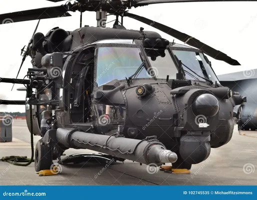 Hélicoptère MH-60 Black Hawk des forces spéciales noir, garé sur un tarmac avec sa porte ouverte et du matériel à l'extérieur.