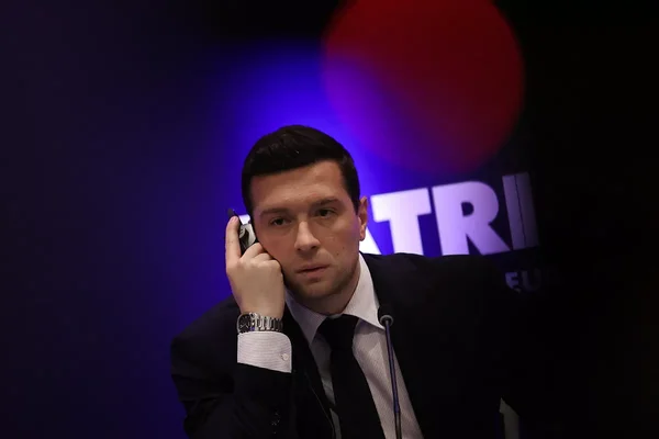 Jordan Bardella téléphonant lors d'un événement.