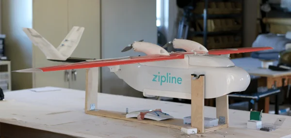 Des techniciens en gilets jaunes préparant un drone Zipline sur un site de distribution.