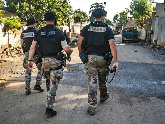 Des gendarmes en tenue camouflée patrouillent dans une rue de Mayotte.