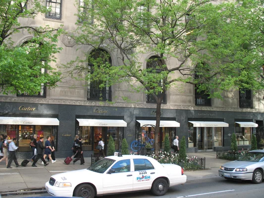 Boutique Cartier et Van Cleef & Arpels avec un taxi FLASH stationné devant, dans une rue de Paris.
