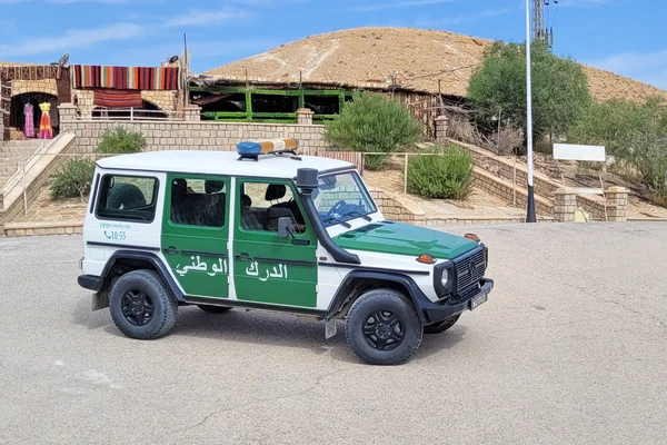 Foule rassemblée la nuit comprenant des forces de l'ordre et des civils éclairés par les réverbères.