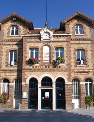 L'hôtel de ville de Noisiel identifiable par son horloge et ses drapeaux sous un ciel bleu.