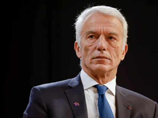 Patrick Martin en costume et cravate bleue devant un fond sombre.