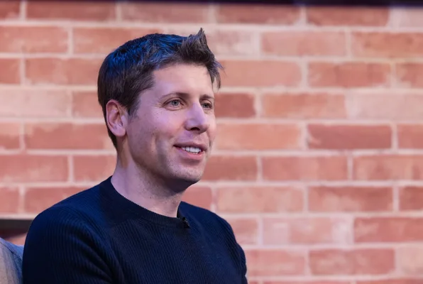 Sam Altman lors d'un entretien assis face à un mur de briques.