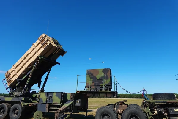 Une batterie de missiles Patriot américaine déployée avec son système radar dans un champ.