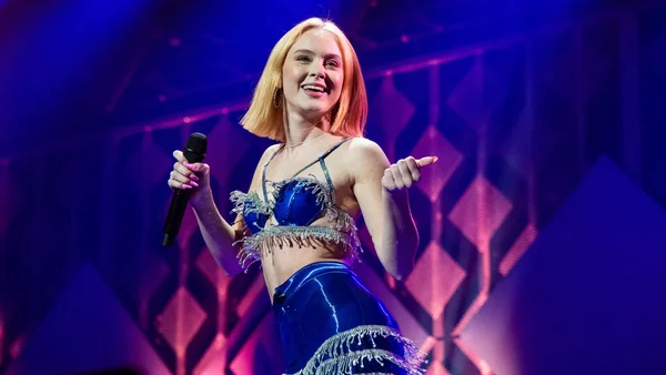 Zara Larsson en performance scénique portant une tenue bleue à franges.