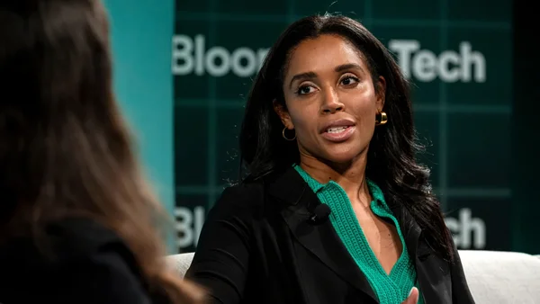 Sarah Bond en conversation lors d'un événement Tech, portant blazer noir et haut vert.