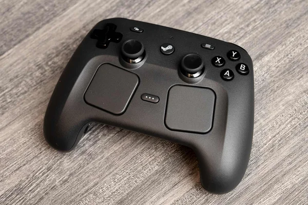 Le Steam Controller de Valve posé sur un support en bois gris.