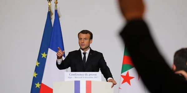 Réunion diplomatique près du drapeau tricolore dans le cadre des discussions France-Algérie.
