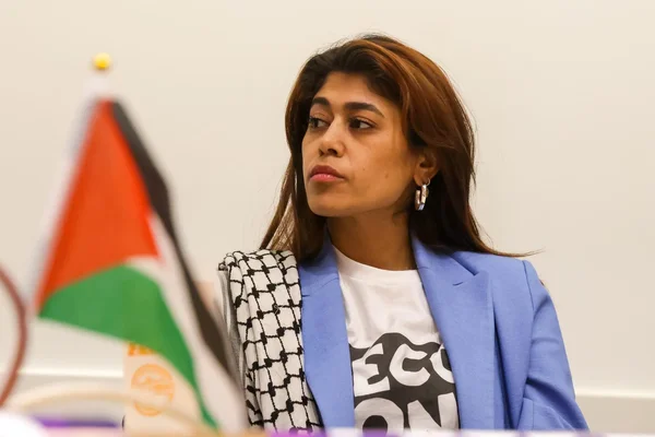 Rima Hassan après son expulsion d'Israël à bord du bateau Madleen, avec un drapeau palestinien visible derrière elle.