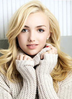 Peyton Roi List posant avec un pull en maille beige.