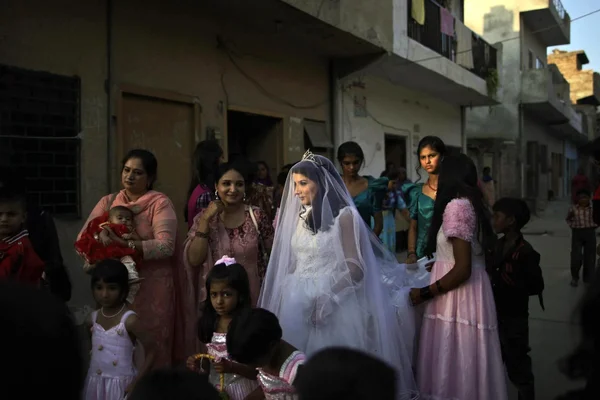 Une mariée en robe blanche au milieu de la foule lors d'une célébration de rue.