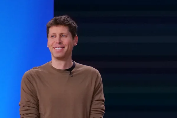 Sam Altman souriant devant un fond dégradé bleu.