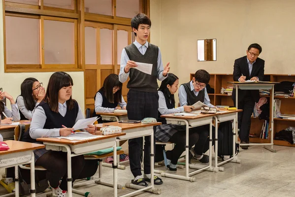 Un étudiant se tient devant la classe dans un établissement scolaire coréen.