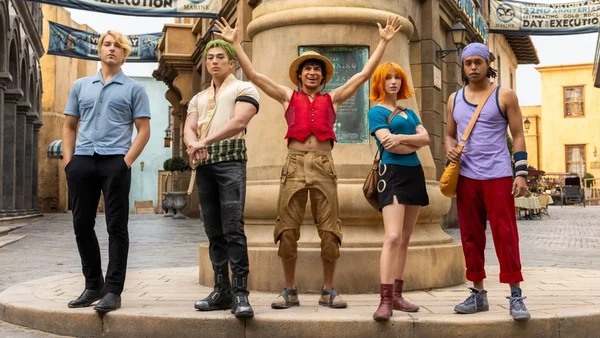 Les acteurs de One Piece live-action devant les décors de l'exécution avec les bannières Marines.