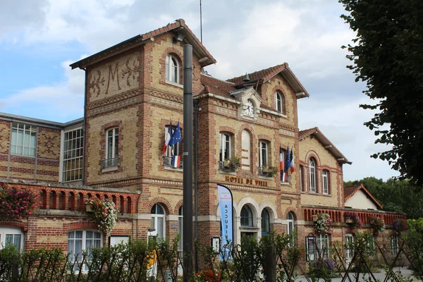 L'hôtel de ville de Noisiel avec son architecture en briques, son horloge et ses drapeaux.