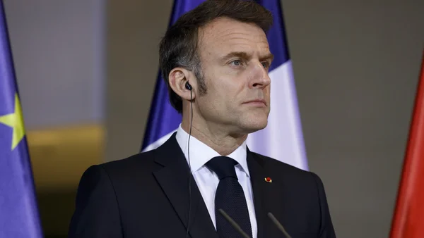 Un homme en costume debout devant les drapeaux français et européen lors d'un événement officiel.