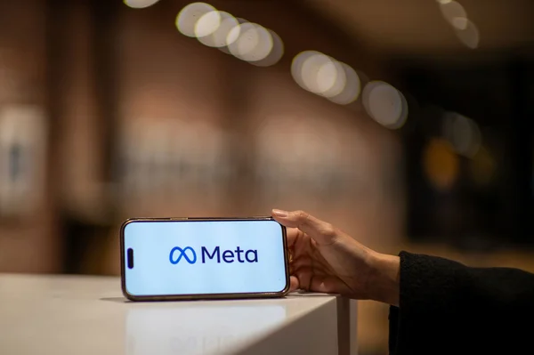 Smartphone affichant le logo de Meta tenu par une main.
