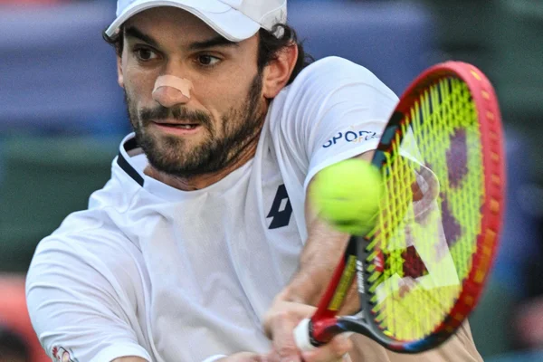 Valentin Vacherot frappant la balle en match, portant une casquette blanche et un polo.