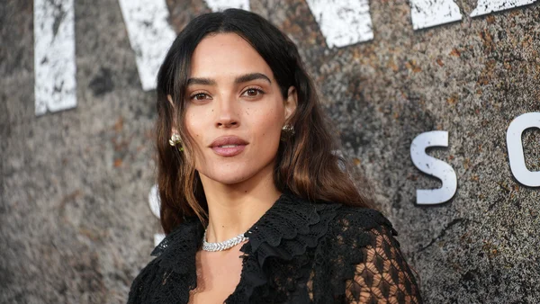 Adria Arjona posant devant un mur texturé.