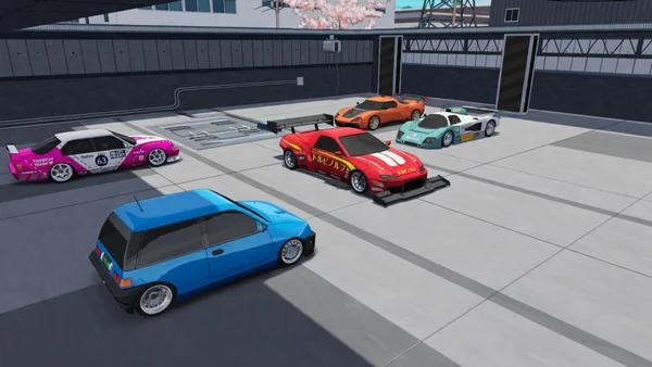 Cinq véhicules variés, dont une voiture de course rose numéro 63, garés devant des bâtiments industriels.