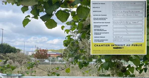 Un panneau de chantier relatif au projet de mosquée à Magny-les-Hameaux devant les bâtiments en arrière-plan.