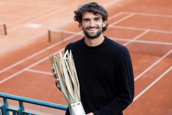 Valentin Vacherot posant avec un trophée ATP sur l'ocre d'un court de tennis.