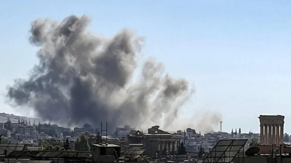 Panache de fumée noire au-dessus de Beyrouth après des frappes israéliennes, avec des colonnes antiques en premier plan.
