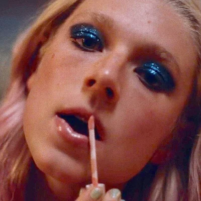 Plan rapproché sur l'application d'un produit à lèvres accompagné d'un maquillage des yeux bleu électrique.