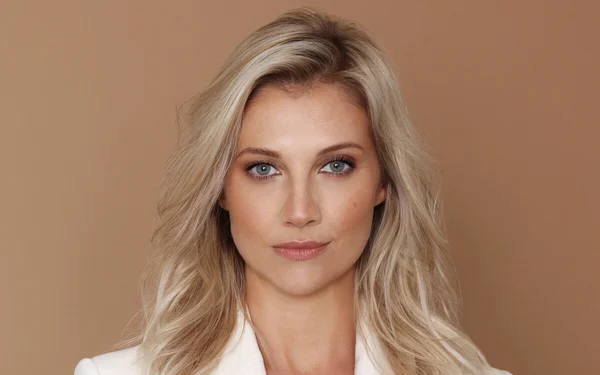 Audrey Lefèvre en portrait, portant un haut blanc sur fond marron.