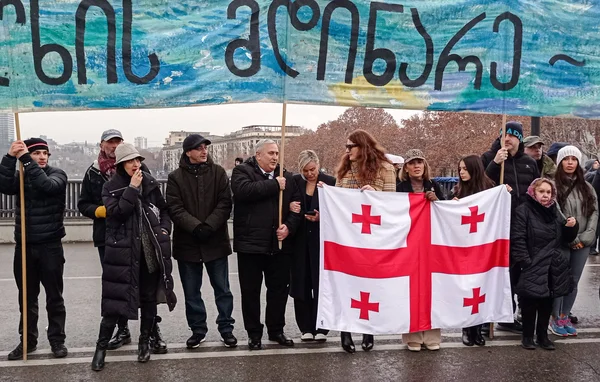 Manifestation pro-européenne avec bannière et drapeau national en Géorgie.