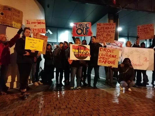 Manifestation nocturne avec des panneaux revendicatifs devant le collège.